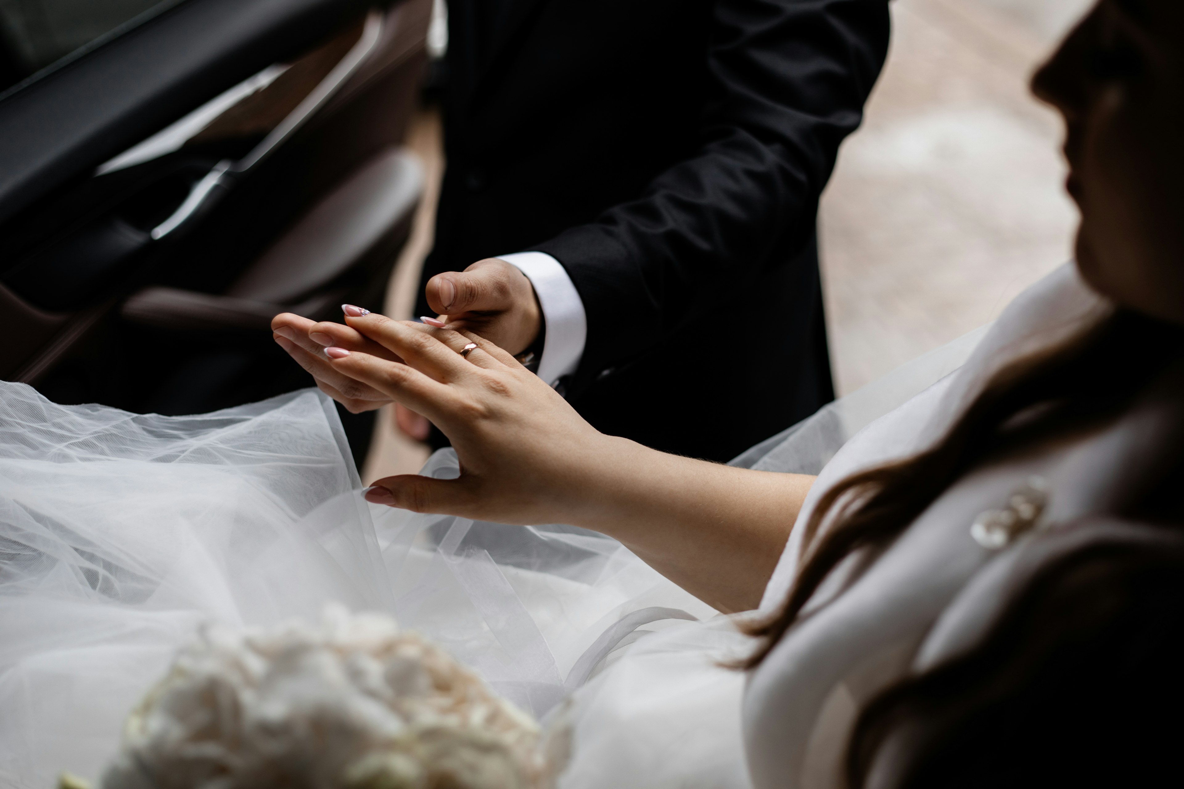 Newlywedds in a limo holding hands.